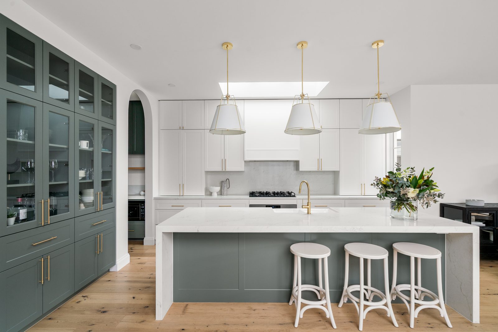 Green kitchen with brass pendants